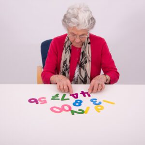 an old woman sitting at a table with numbers on it
